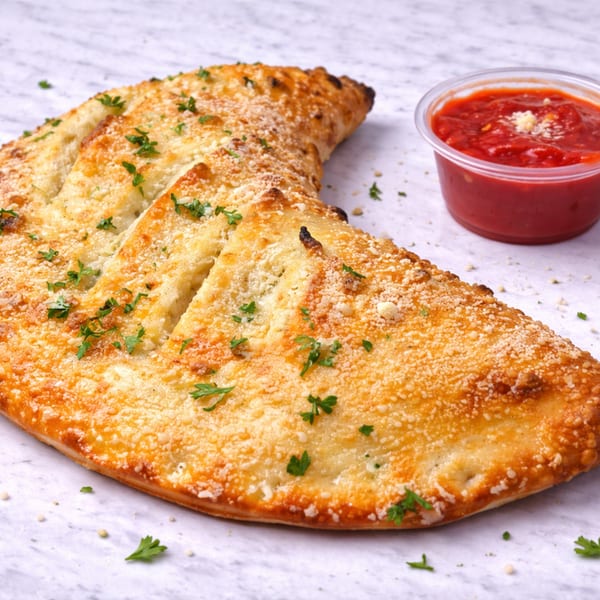 Golden-brown calzone sprinkled with parmesan cheese and parsley, served with a side of marinara sauce.
