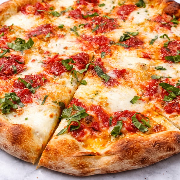 A close-up of a freshly baked pizza with melted cheese, red sauce, and green basil leaves.