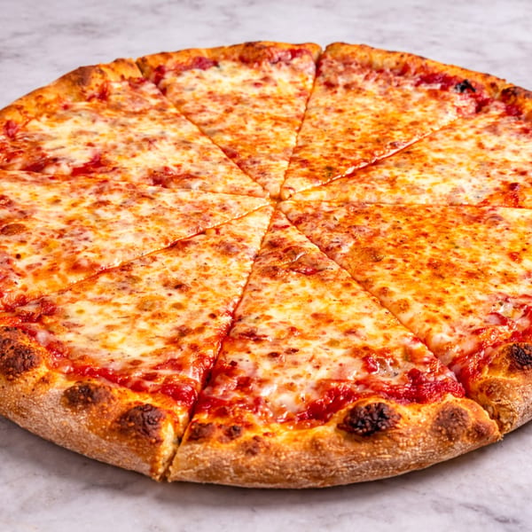 A whole cheese pizza, cut into eight slices, on a white marble surface.